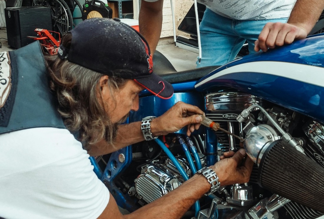 Photo d'un homme pratiquant de la mécanique sur une moto