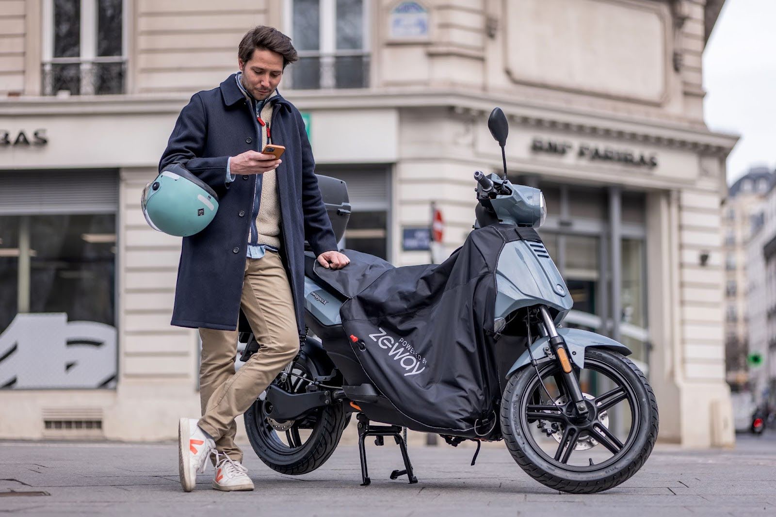 Photographie d'un motard avec son scooter électrique en zone urbaine